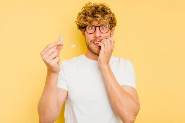 Junger Kaukasischer Mann Mit Hörgerät Isoliert Auf Gelbem Hintergrund Beißt — Stockfoto