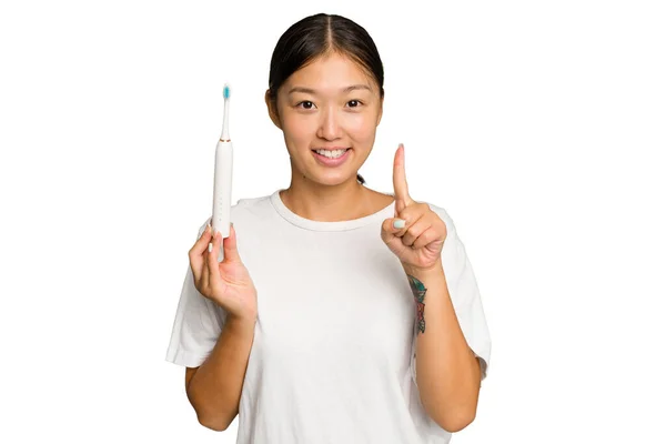年轻的亚洲女人拿着一把用绿色底色隔离的电动牙刷 带着第一指尖 — 图库照片