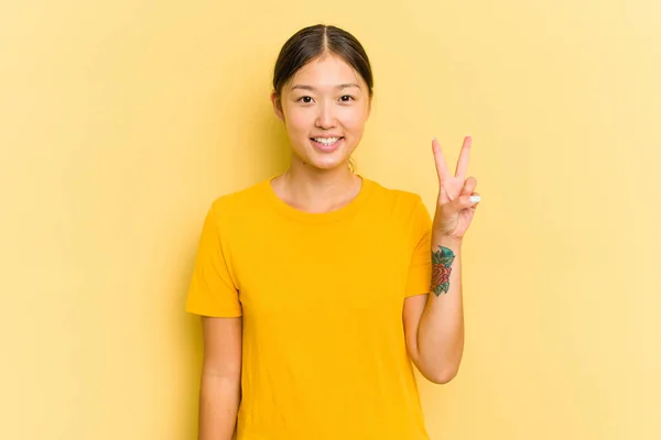 Junge Asiatin Isoliert Auf Gelbem Hintergrund Zeigt Siegeszeichen Und Lächelt — Stockfoto