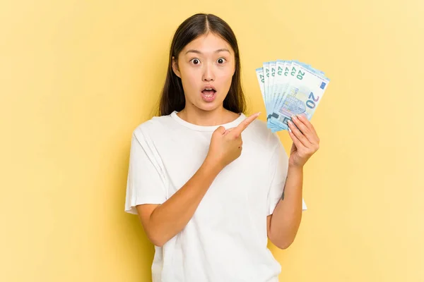Mujer Asiática Joven Sosteniendo Billete Aislado Sobre Fondo Amarillo Apuntando — Foto de Stock
