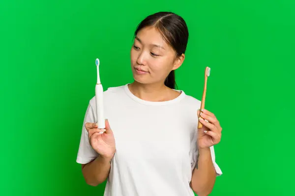 Elinde Elektrikli Diş Fırçası Olan Asyalı Genç Bir Kadın Yeşil — Stok fotoğraf