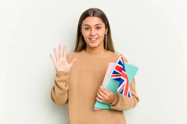 Young Indian woman holding an United Kingdom flag isolated on white background smiling cheerful showing number five with fingers.