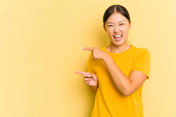 年轻的亚洲女人 背景是黄色的 食指指向一个复制的空间 表示兴奋和渴望 — 图库照片