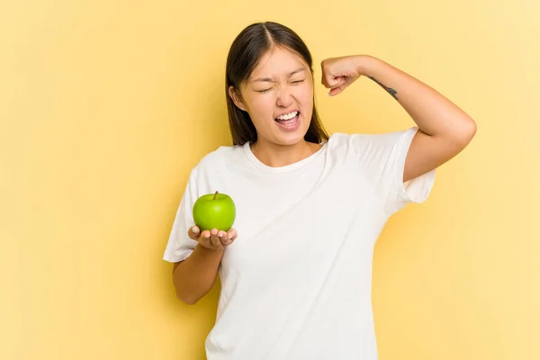 Young Asian Woman Eating Apple Isolated Yellow Background Raising Fist — Stock Photo, Image