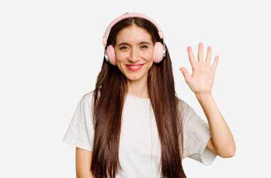 Kafkasyalı kulaklık takan genç bir kadın izole edilmiş gülümseyen beş numarayı parmaklarıyla gösteriyor..