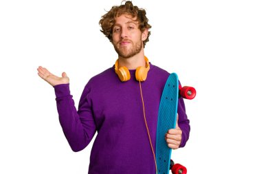 Young skater caucasian man isolated on white background showing a copy space on a palm and holding another hand on waist.