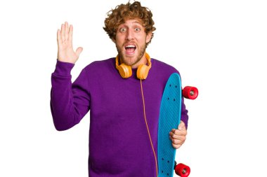 Young skater caucasian man isolated on white background receiving a pleasant surprise, excited and raising hands.