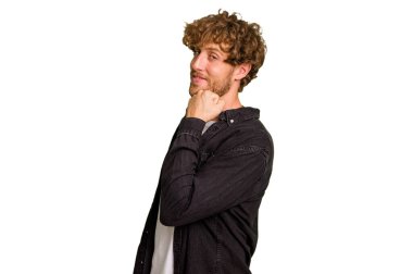 Yeşil krom arka planda izole edilmiş genç beyaz adam gülümsüyor ve kendinden emin, çenesine elle dokunuyor..