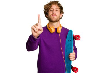 Young skater caucasian man isolated on white background showing number one with finger.