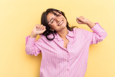 Sarı arka planda izole edilmiş genç bir Hintli kadın. Kollarını uzatıyor, rahat duruyor..