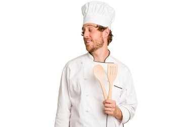 Genç aşçı beyaz arka planda izole edilmiş gülümseyen, neşeli ve keyifli görünüyor..