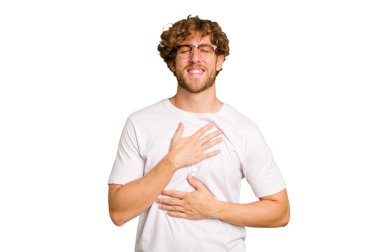 Yeşil krom arka planda izole edilmiş genç beyaz adam mutlu bir şekilde gülüyor ve ellerini karnının üstünde tutarak eğleniyor..