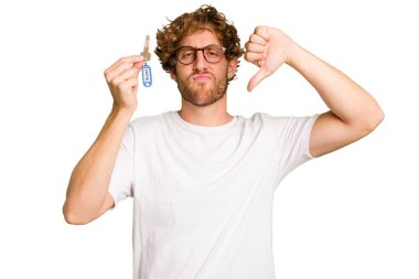 Beyaz arka planda izole edilmiş, hoşlanmadığı bir hareket gösteren ev anahtarlarını elinde tutan beyaz bir adam. Anlaşmazlık konsepti.