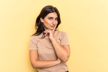 Sarı arka planda izole edilmiş genç Hintli kadın bir strateji planlıyor, bir iş yolu düşünüyor..