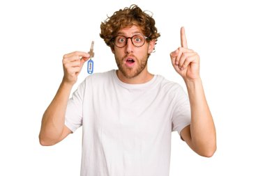 Beyaz arka planda izole edilmiş ev anahtarlarını elinde tutan genç beyaz adamın bir fikri var, ilham verici bir kavram..