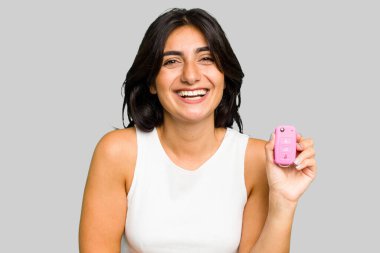 Elinde araba anahtarı olan genç Hintli bir kadın eğleniyor ve gülüyor..