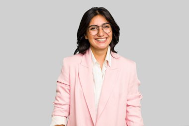 Pembe takım elbiseli genç Hintli iş kadını yalnız, mutlu, güler yüzlü ve neşeli..