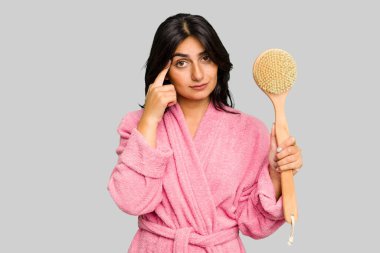 Sırt kaşıyıcısı tutan bornozlu genç Hintli bir kadın. Bir tapınağı parmağıyla işaret ediyor, düşünüyor, bir göreve odaklanıyor..