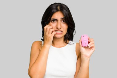 Araba anahtarı tutan genç Hintli kadın tırnak yiyor, gergin ve endişeli..