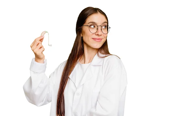 Νεαρή Ωτορινολαρυγγολόγος Καυκάσιος Γυναίκα Κρατώντας Ακουστικό Απομονωμένη Κοιτάζει Πέρα Χαμογελαστή — Φωτογραφία Αρχείου