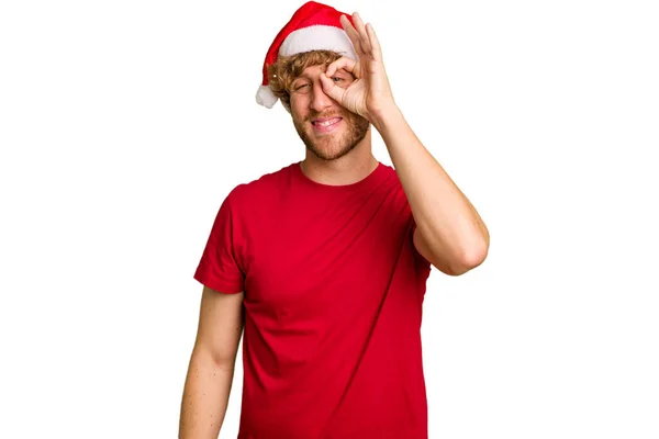 年轻的高加索人头戴一顶白色背景的圣诞圣诞圣诞圣诞礼帽 兴奋得目瞪口呆 — 图库照片