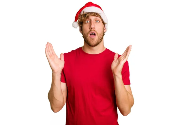 若いですCaucasian男身に着けていますAクリスマスサンタ帽子隔離上の白い背景驚きとショック — ストック写真