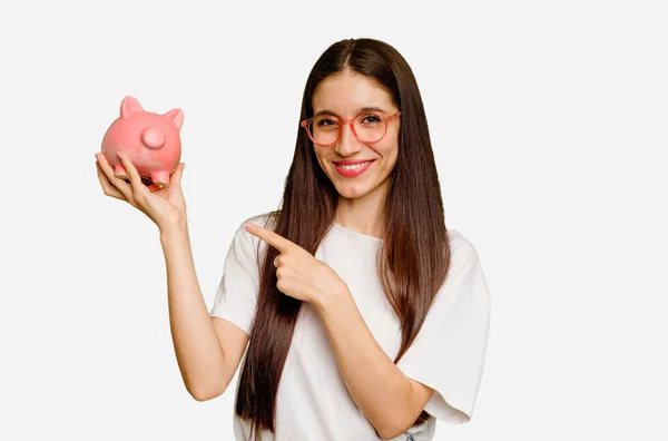 Joven Mujer Caucásica Sosteniendo Una Alcancía Aislada Sonriendo Señalando Lado — Foto de Stock