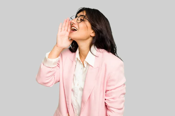 若いですインドのビジネス女性を身に着けていますピンクのスーツ隔離された叫びと保持手のひら近くオープン口 — ストック写真