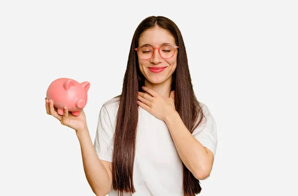 Young Caucasian Woman Holding Piggy Bank Isolated Laughs Out Loudly — Stock Photo, Image