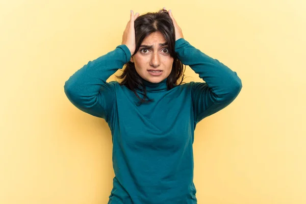 若いインド人女性は耳を覆う黄色の背景に孤立し 手で大きすぎる音を聞かないようにしています — ストック写真
