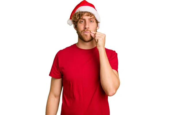 若いですCaucasian男身に着けていますAクリスマスサンタ帽子隔離された上の白い背景に指で唇に秘密を保ちます — ストック写真
