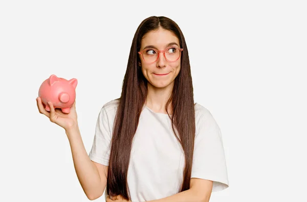 Young Caucasian Woman Holding Piggy Bank Isolated Confused Feels Doubtful — Stock Photo, Image