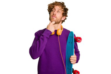 Young skater caucasian man isolated on white background looking sideways with doubtful and skeptical expression.