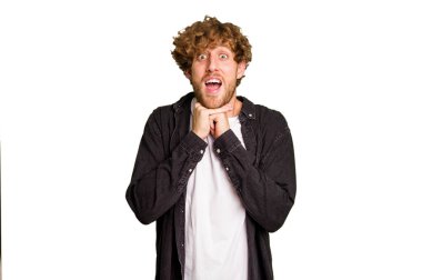 Kafkasyalı genç adam yeşil krom arka planda izole edilmiş şans için dua ediyor, şaşırıyor ve ağzını açıyor..