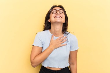 Sarı arka planda izole edilmiş genç Hintli kadın kahkahalar atıyor..