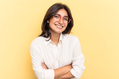 Sarı arka planda yalnız yaşayan genç Hintli kadın gülüyor ve eğleniyor..