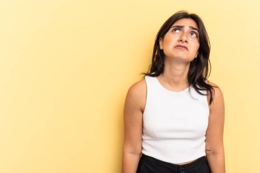 Sarı arka planda izole edilmiş genç Hintli kadın çok kızgın, öfkeli, hayal kırıklığına uğramış.