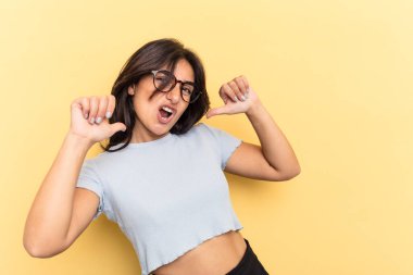 Sarı arka planda izole edilmiş genç Hintli kadın gururlu ve kendinden emin hissediyor, örnek olarak..