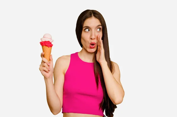 年轻的高加索女人吃着被隔离的冰淇淋 说着一个秘密的热刹车新闻 并把目光投向了旁边 — 图库照片