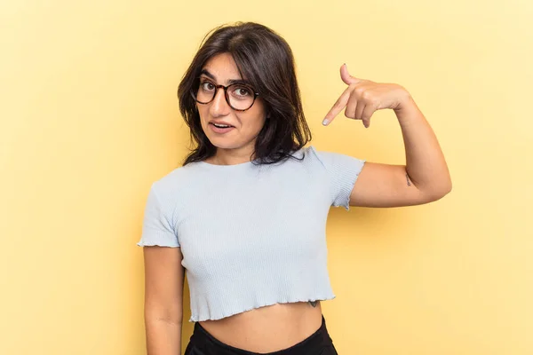 黄色の背景の人に手でシャツのコピースペースを指して隔離された若いインド人女性 誇りと自信 — ストック写真