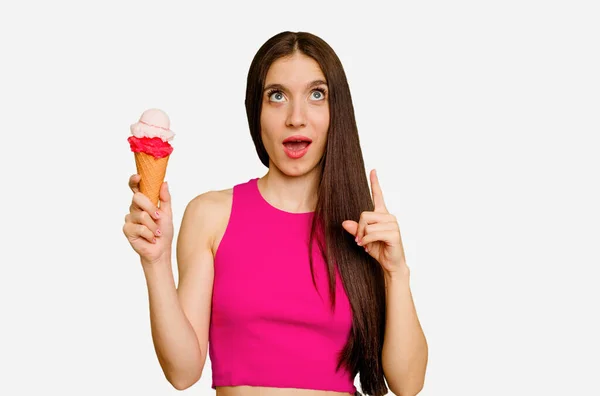 年轻的高加索女人吃着一种冰淇淋 这种冰淇淋孤立地指向上头 张着嘴 — 图库照片