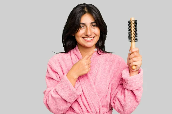 Mujer India Joven Albornoz Sosteniendo Cepillo Aislado Sonriendo Señalando Lado — Foto de Stock