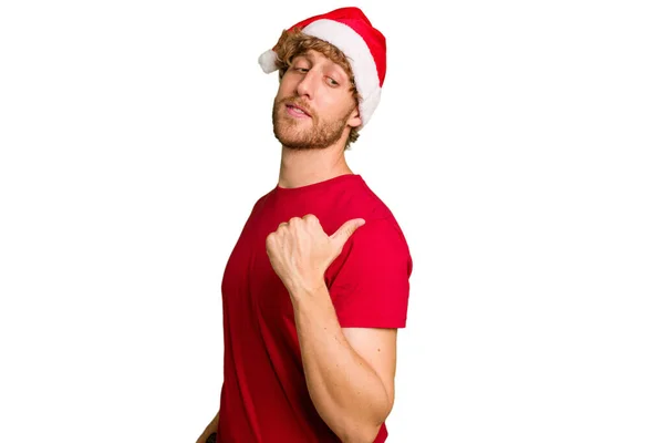 若いですCaucasian男身に着けていますAクリスマスサンタ帽子隔離された上の白い背景点とともに親指指離れて 笑いと屈託のない — ストック写真