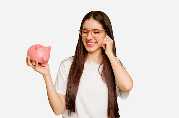 Young Caucasian Woman Holding Piggy Bank Isolated Covering Ears Hands — Stock Photo, Image