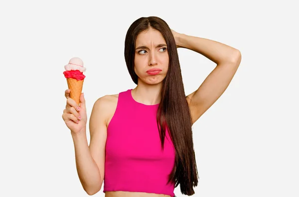 年轻的高加索女人吃着冰淇淋 孤立地碰了碰后脑勺 思考着 做出了选择 — 图库照片
