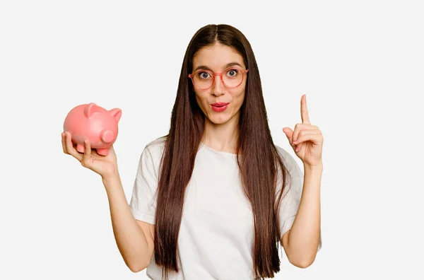 Young Caucasian Woman Holding Piggy Bank Isolated Having Idea Inspiration — Stock Photo, Image