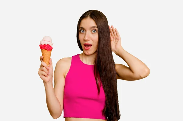 年轻的高加索女人吃着冰淇淋 孤立地听着流言蜚语 — 图库照片