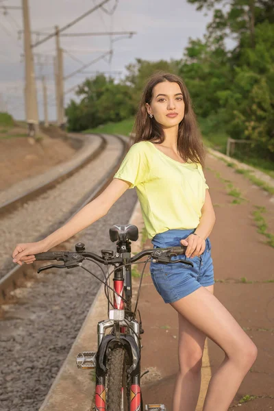 Güzel bir Slav genç kız bisikletle poz veriyor. Genç bir kız şehir dışında bisikletle yürüyor..
