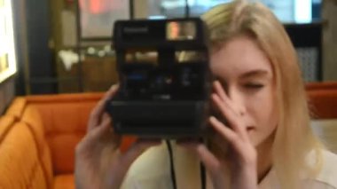 Fotoğrafçı kız elinde fotoğraf makinesi tutuyor. Genç bir fotoğrafçı kız, bir kafede fotoğraf çekiyor. Kız elinde bir kamera tutuyor ve fotoğraf çekmeye gidiyor.. 