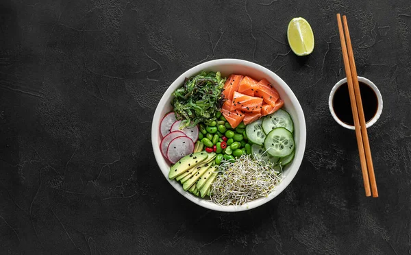 Keto dieta poke bowl con salmone, avocado, e fagioli edamame. su sfondo scuro. Immagini Stock Royalty Free